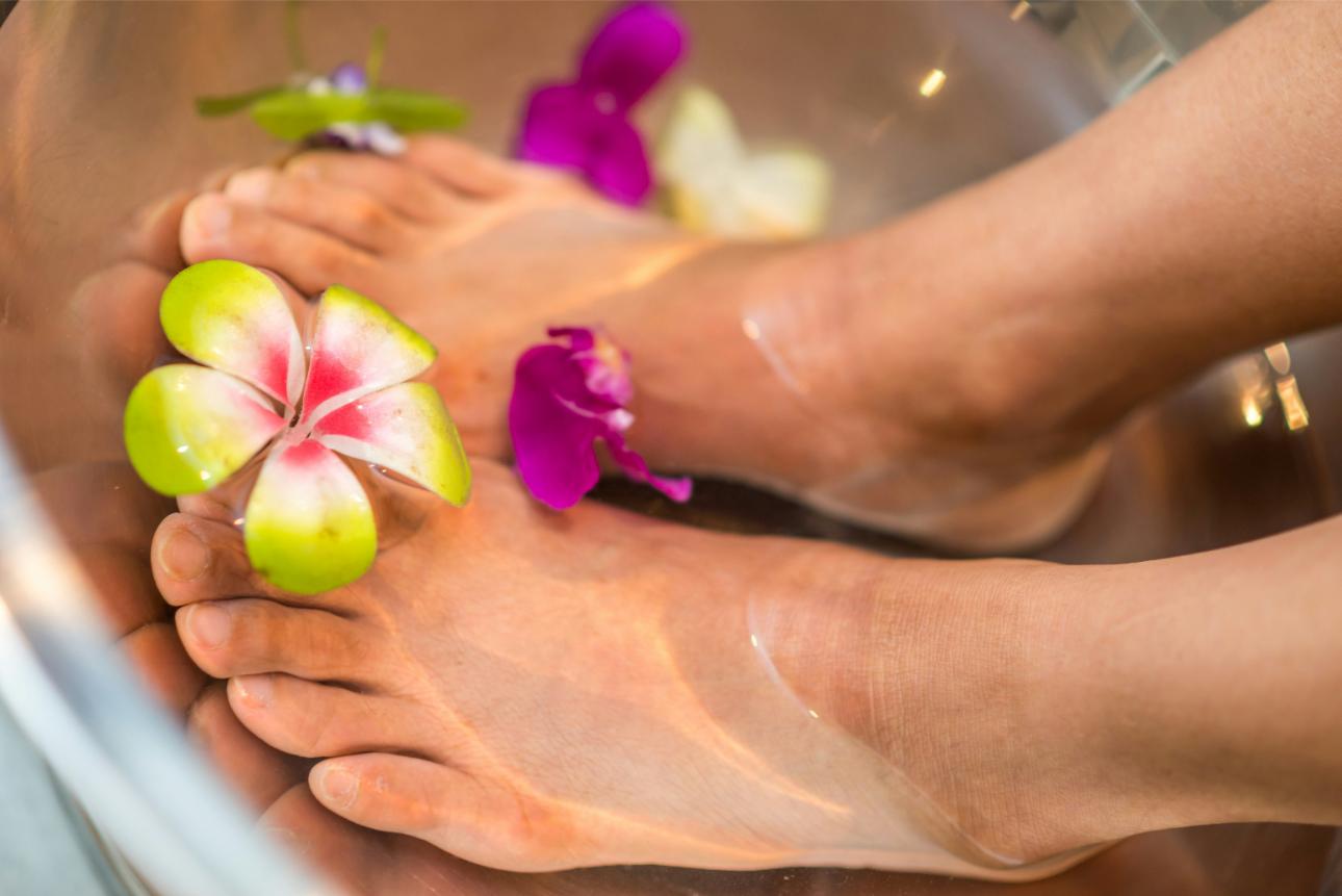 Füße in Blütenwasser mit Blumen